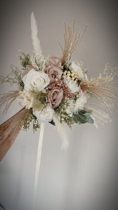 a bridal bouquet with feathers, flowers and foliage on the top is ready to be used as a corsage