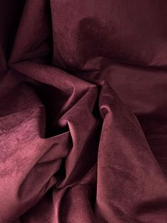 an up close shot of the fabric on a bed sheet that has been made in dark red