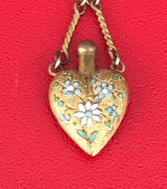 This charming necklace is made in the style of the Victorian vinaigrete pendant which was used in Victorian times to mask the not so pleasant odors. The vase shaped pendant is beautifully decorated with enamel blue and white flowers. The chain is marked 12K G.F. The chain is 12" long and the necklace with the pendant is 16" long. There are signs of wear to the gold and chips to the enamel, but this is still a gentle and lovely piece! Please see all photos for details, as well as, condition. Than Antique Enamel Necklaces For Wedding, Antique Enamel Necklace For Wedding, Wedding Pendant Necklace In Enamel, Ornate Enamel Necklaces For Gifts, Enamel Locket Pendant Necklace, Filigree Diamond Ring, Blue And White Flowers, Victorian Times, Heart Shaped Frame