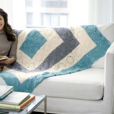 a woman sitting on a couch holding a book in her hands and smiling at the camera