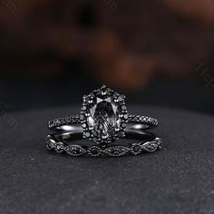 an oval shaped engagement ring with black diamonds on the band and side stones in the center