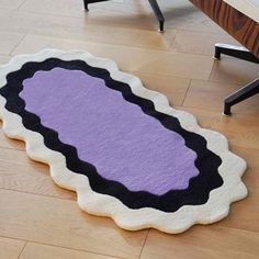 a purple and black rug sitting on top of a wooden floor next to a table