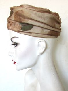 **MARCHE EXCLUSIVE Well-made, from a respected maker, this is a sophisticated late mid-century hat. It has fine netting over cloth leaves in beige, brown and green and is fashioned with folds of fabric to make a pillbox style. The crown is a spiral of folds and the hat is a semi-hard body, sturdy enough to stand on its own.  Very good vintage condition Size 22  SHIPPING NOTES -Smalls and lightweight items ship Ground -Free shipping goes Ground -Shipping upgrade and expedited incur additional fee 1960s Hats, Hard Body, Brown And Green, Cloche Hat, Pill Boxes, Beige Brown, The Crown, First Class, Etsy Accessories