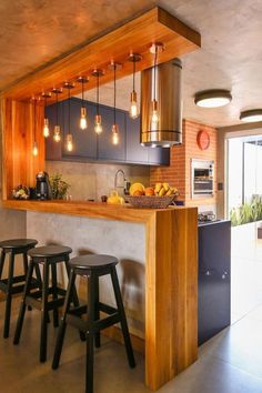 a kitchen with three stools next to a counter and some lights hanging from the ceiling