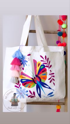 a colorful butterfly tote bag with pom - poms hanging from it's side