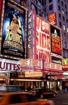 a busy city street filled with lots of neon signs and cars driving past tall buildings