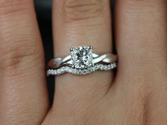 a woman's hand with a diamond ring on top of her wedding band and an engagement ring in the middle