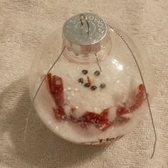 a snowman ornament that is sitting on the ground with something in it