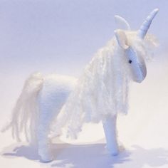 a white stuffed unicorn standing on top of a snow covered ground