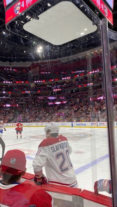 a hockey player sitting on the bench in front of an ice rink with fans watching