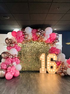 a large balloon arch with the number sixteen surrounded by pink, white and gold balloons