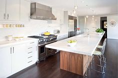 a modern kitchen with white cabinets and wood flooring, stainless steel appliances and counter tops