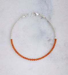 Indulge in the fiery beauty of Carnelian, the orange variety of quartz known for enhancing passion, love, and desire. This stone is also believed to bring confidence, prosperity, and good luck, as well as promote fertility, improve circulation, and alleviate depression. This bracelet is handmade with tiny, smooth polished round Carnelian gemstones surrounded by gold or silver beads. It is available in sterling silver or 14k gold fill. Stone Size: average 2mmStone Bar Length: 3" (7.6cm) Orange Beaded Bracelets, Orange Carnelian, Carnelian Bracelet, Carnelian Beads, Improve Circulation, Energy Stones, Nature Bracelets, Light Orange, Gemstone Bracelet