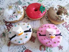 four decorated doughnuts with frosting, sprinkles and decorations on them