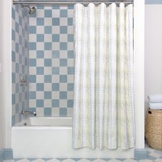 a bath tub sitting next to a shower curtain in a bathroom with blue and white tiles on the walls