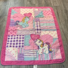 a pink and purple quilted blanket with ponys on the front, two hearts in the back