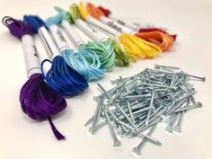 several skeins of thread and needles on a white table with colorful yarn in the background