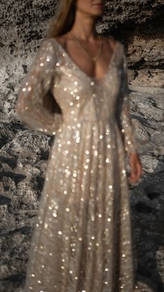 a woman in a white dress standing on rocks