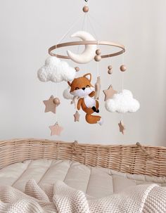 a baby crib with a stuffed fox hanging from it's side and stars on the ceiling