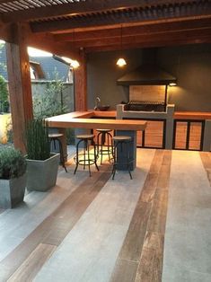 an outdoor kitchen and dining area with potted plants in the foreground, surrounded by wooden flooring