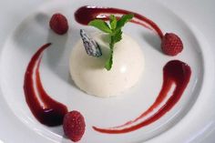 a white plate topped with a dessert covered in raspberry sauce and garnish