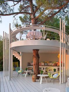 a tree is growing in the middle of a deck area that has chairs and tables on it