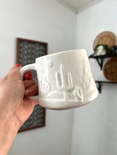 a person holding a white coffee mug in their hand