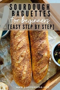 two large baguettes sitting on top of a wooden tray next to bowls of food