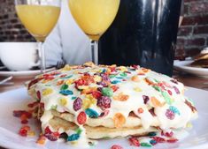 a white plate topped with cake covered in sprinkles next to two glasses of orange juice