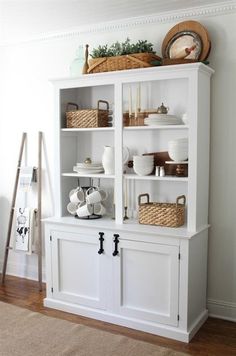 a white bookcase with baskets and dishes on it