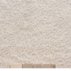 a close up view of a white rug with wood planks on the bottom floor