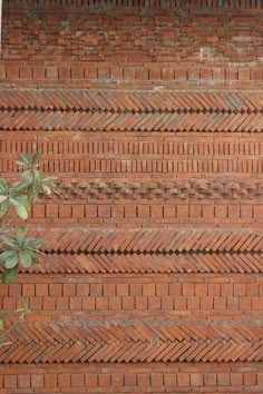 a red brick wall with green leaves on it