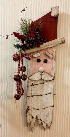 a wooden santa clause hanging from the side of a wall with pine cones on it