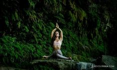 a woman sitting on top of a rock next to a lush green forest