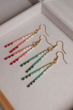 five pairs of earrings in a box on the table, with one earring dangling down