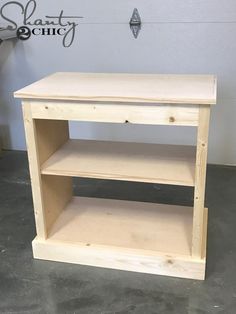 a wooden shelf sitting on top of a cement floor next to a white sign that says,