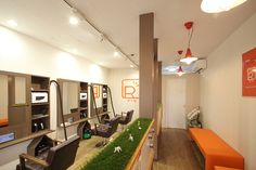 the interior of a hair salon with grass growing on the floor and chairs in front of it