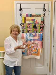 a woman standing in front of a wall hanging quilt