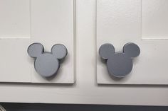 two mickey mouse magnets are attached to the front of a white door with gray trim