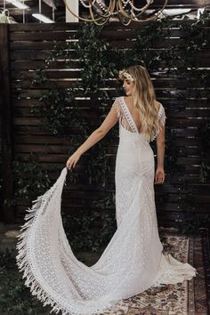 a woman in a white wedding dress standing on a rug with her back to the camera