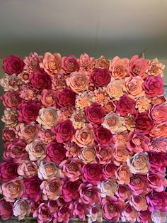 an arrangement of pink and orange flowers on a wall