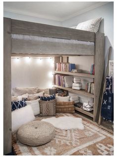 a loft bed with bookshelves and pillows on the bottom bunk is made out of wood