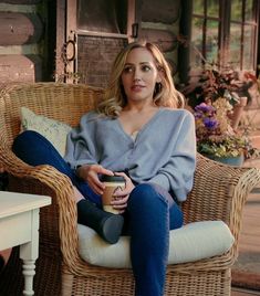 a woman sitting in a wicker chair holding a cup