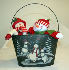 two stuffed snowmen sitting in a bucket