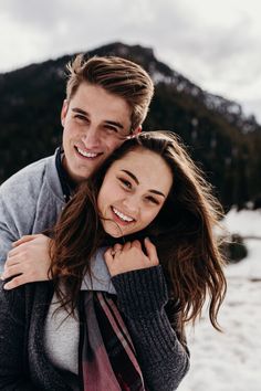 a young man and woman are hugging in the snow