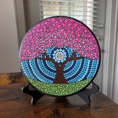 a colorful glass plate with a tree on it sitting on top of a wooden table