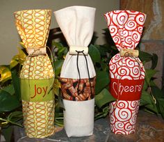 three wine bottles wrapped in fabric and tied together with ribbon, sitting next to each other