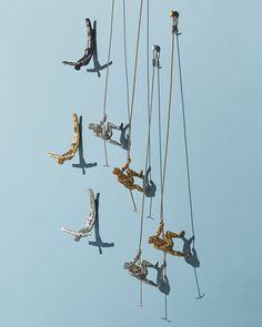 several people hanging from ropes in the air with their feet dangling off one pole and holding onto chains