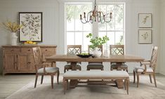 a dining room table with chairs and a bench in front of it, next to a window