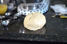 a ball of dough sitting on top of a counter next to measuring cups and spoons